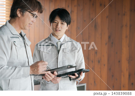 打ち合わせをする作業着の男性 143839088