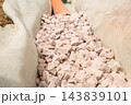 Small gravel stones fill a trench around an orange drainage pipe. The construction site shows a well organized stone base designed for effective water management solutions. 143839101