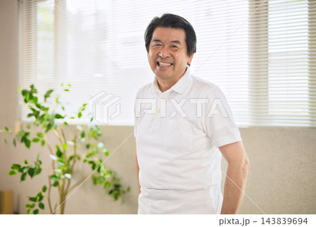 窓際に立つ笑顔のシニア男性 143839694