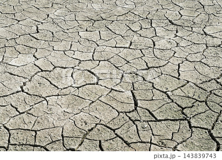 ひび割れた乾燥した大地のテクスチャ背景（干ばつ・地球温暖化・水不足・乾燥・土・地表・自然災害） 143839743