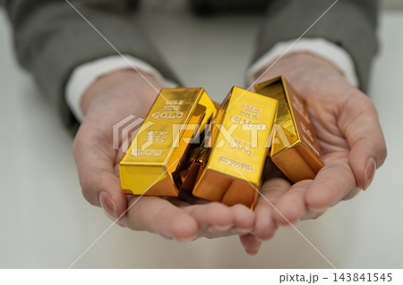 Asian woman holding gold bar in finance business. Asian woman holding gold bar in finance business. 143841545