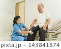 Healthcare professional assessing senior man's knee pain in clinic. 143841874