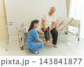 Nurse assisting senior man with leg pain at home for better mobility 143841877