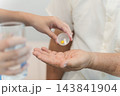 Caregiver administering medication to senior adult for health management 143841904