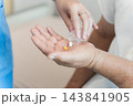 Healthcare professional dispensing medication to senior patient at clinic 143841905
