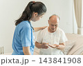 Nurse assisting elderly patient with medication in home care setting. 143841908