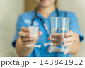Healthcare professional administering medication with water in clinic 143841912