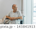 Senior Asian man sitting in wheelchair at home, reflecting on life. 143841913
