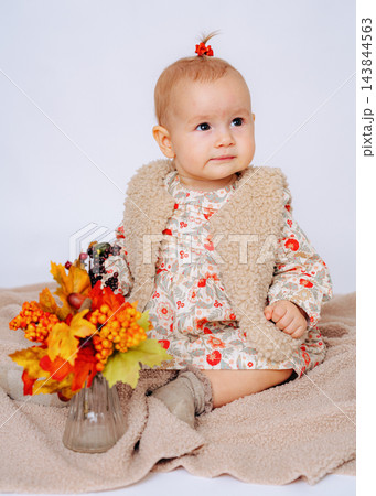 Cute infant girl posing in a cozy studio environment with warm fall decor, capturing natural childhood expressions, innocence, and seasonal beauty Cute infant girl posing in a cozy studio environment with warm fall decor, capturing natural childhood expressions, innocence, and seasonal beauty 143844563