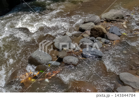 Wet river rocks and pebbles in shallow flowing water natural stone texture background Wet river rocks and pebbles in shallow flowing water natural stone texture background 143844784