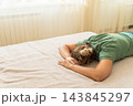 Woman lying face down on a bed, appearing exhausted and taking a nap, resting after a long day or experiencing burnout 143845297