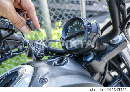 大型アメリカンバイクのイグニッションキーを差し込む男性の手元 大型アメリカンバイクのイグニッションキーを差し込む男性の手元 143845553
