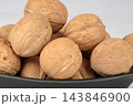 Extreme close up view of whole unshelled raw walnuts filled in a black ceramic bowl 143846900