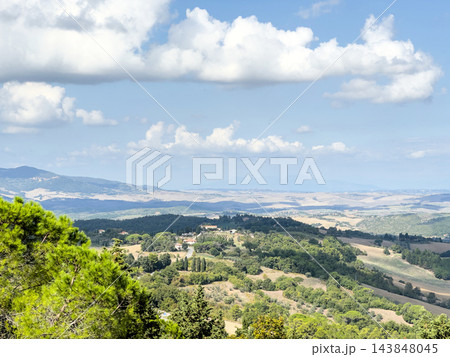 Tuscan countryside with farms and distant hazy plains under cumulus clouds Tuscan countryside with farms and distant hazy plains under cumulus clouds 143848045