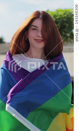 Vertical video. Young woman covering herself in lgbt flag while walking on the street. Vertical video. Young woman covering herself in lgbt flag while walking on the street. 143848306