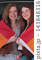 Vertical video. Young lesbian couple taking selfie and sit in the back of the car. Two happy girlfriends pose with rainbow flag. Lgbt woman, showing love to. 143848316