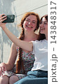 Vertical video. Young adult lesbian couple taking selfie in the city. Two happy girlfriends pose with rainbow flag. Lgbt woman, showing love to each other. 143848317