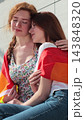 Vertical video. Lesbian couple Embrace, smiling sitting on bench wrapped in rainbow flag. Pride concept. 143848320