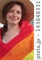 Vertical video. Portrait of a young woman in a hat with long red hair covering herself in lgbt flag while looking to camera. 143848331