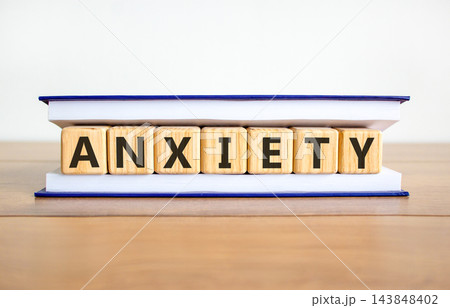 Anxiety word symbol. Concept word Anxiety on beautiful wooden blocks in book. Beautiful wooden table white background. Business medical anxiety word concept. Copy space. 143848402