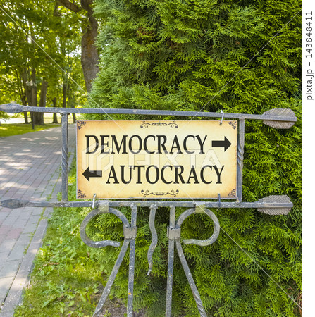 Democracy or autocracy words symbol. Concept words Democracy Autocracy on beautiful information road sign. Beautiful green tree background. Business democracy autocracy concept. Copy space 143848411