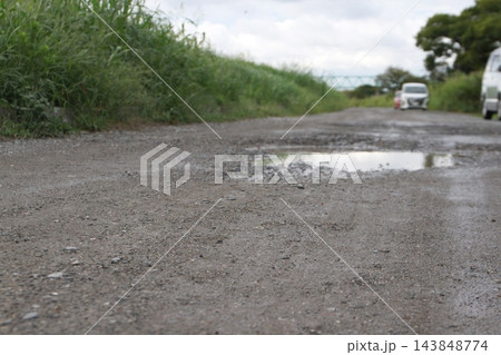 雨上がりの水たまりができる未舗装の未舗装路と河川敷の道 雨上がりの水たまりができる未舗装の未舗装路と河川敷の道 143848774