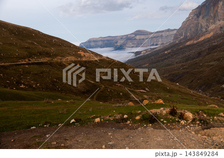 Mountain landscape with winding road and clouds in valley Mountain landscape with winding road and clouds in valley 143849284
