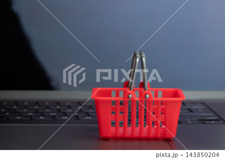 Red plastic shopping basket on laptop background Red plastic shopping basket on laptop background 143850204