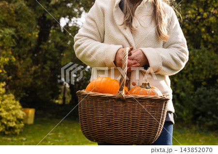 Woman holding Autumn orange pumpkins in vintage basket in countryside 143852070
