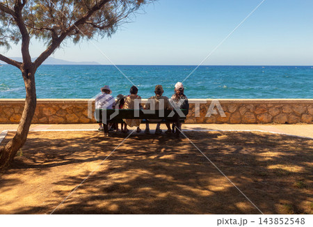 People Sitting on Bench Overlooking the Sea in Chania Crete Greece People Sitting on Bench Overlooking the Sea in Chania Crete Greece 143852548