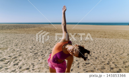 Close view of a woman bending sideways with one arm raised at the beach Close view of a woman bending sideways with one arm raised at the beach 143853366