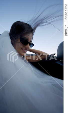 Smiling bride in a white veil beside a car seat 143853568