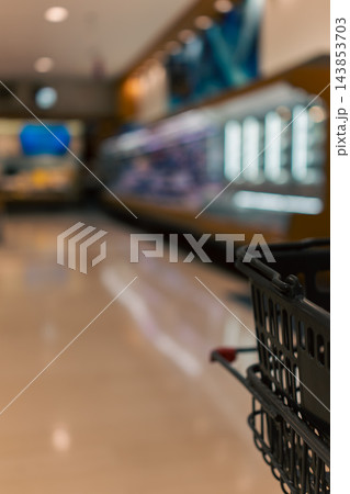 スーパーマーケットの店内とカートに載せた買い物かご スーパーマーケットの店内とカートに載せた買い物かご 143853703