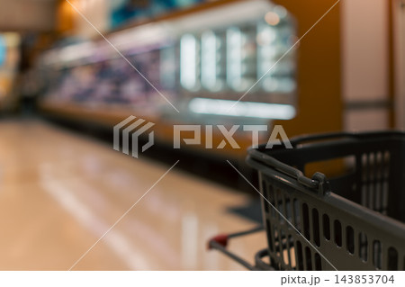 スーパーマーケットの店内とカートに載せた買い物かご スーパーマーケットの店内とカートに載せた買い物かご 143853704