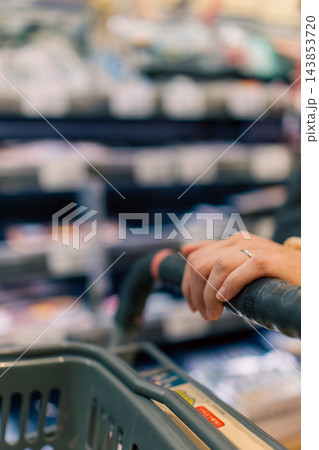 スーパーマーケットの店内とカートに載せた買い物かご スーパーマーケットの店内とカートに載せた買い物かご 143853720