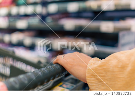 スーパーマーケットの店内とカートに載せた買い物かご スーパーマーケットの店内とカートに載せた買い物かご 143853722