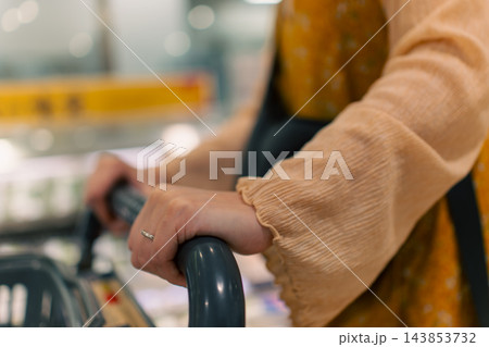 スーパーマーケットの店内とカートに載せた買い物かご スーパーマーケットの店内とカートに載せた買い物かご 143853732