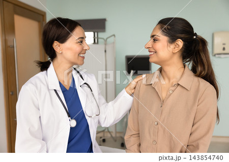 Positive empathetic doctor touching shoulder of happy patient Positive empathetic doctor touching shoulder of happy patient 143854740