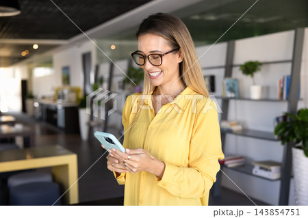 Happy female office employee using smartphone during break at workplace Happy female office employee using smartphone during break at workplace 143854751