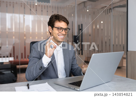 Smiling businessman making okay gesture during video call Smiling businessman making okay gesture during video call 143854821