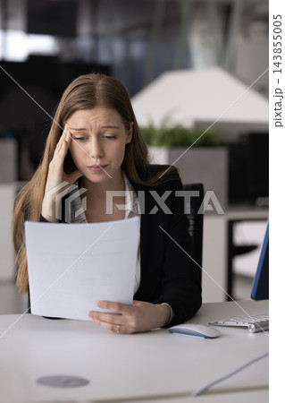 Focused woman executive reading important business document at office desk Focused woman executive reading important business document at office desk 143855005