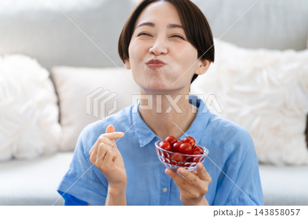 ミニトマトを食べる若い女性 ライフスタイルイメージ ミニトマトを食べる若い女性 ライフスタイルイメージ 143858057