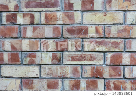 Close-up of a rustic clay brick wall showing colorful brick pattern. Old masonry surface background for building and construction. Close-up of a rustic clay brick wall showing colorful brick pattern. Old masonry surface background for building and construction. 143858601