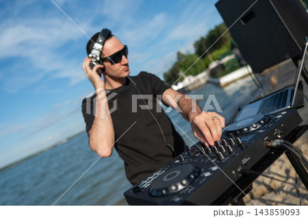 Male DJ playing music on the beach.  143859093