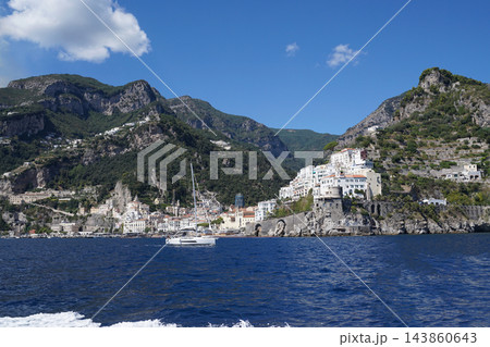 View of beautiful Amalfi town, Campania, Italy. Amalfi coast is most popular travel and holiday destination in Europe. Amalfi cityscape on coast line of mediterranean sea - view from sea View of beautiful Amalfi town, Campania, Italy. Amalfi coast is most popular travel and holiday destination in Europe. Amalfi cityscape on coast line of mediterranean sea - view from sea 143860643
