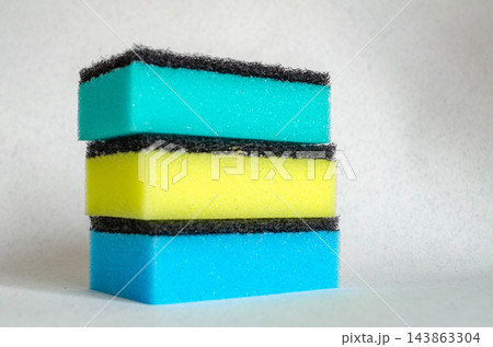 Three stacked kitchen sponges with colored foam and black scrub pads 143863304