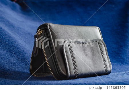 Black leather wallet pouch displayed on blue fabric 143863305