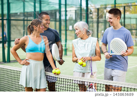 Two pairs of padel players are happily discussing past game on an open court Two pairs of padel players are happily discussing past game on an open court 143863689