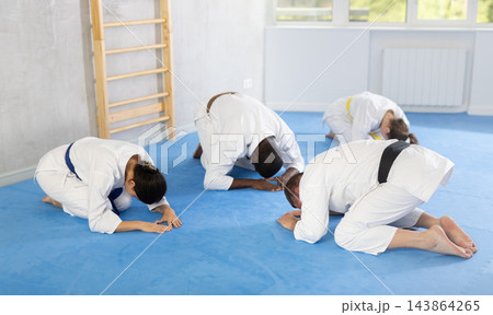 Teacher of martial arts and students sit on floor and make ritual obedience bows greet each other 143864265