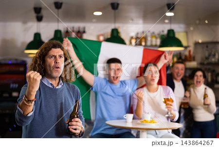 Company of screaming young adult sports fans waving flag of Italy and supporting national team with beer in bar Company of screaming young adult sports fans waving flag of Italy and supporting national team with beer in bar 143864267